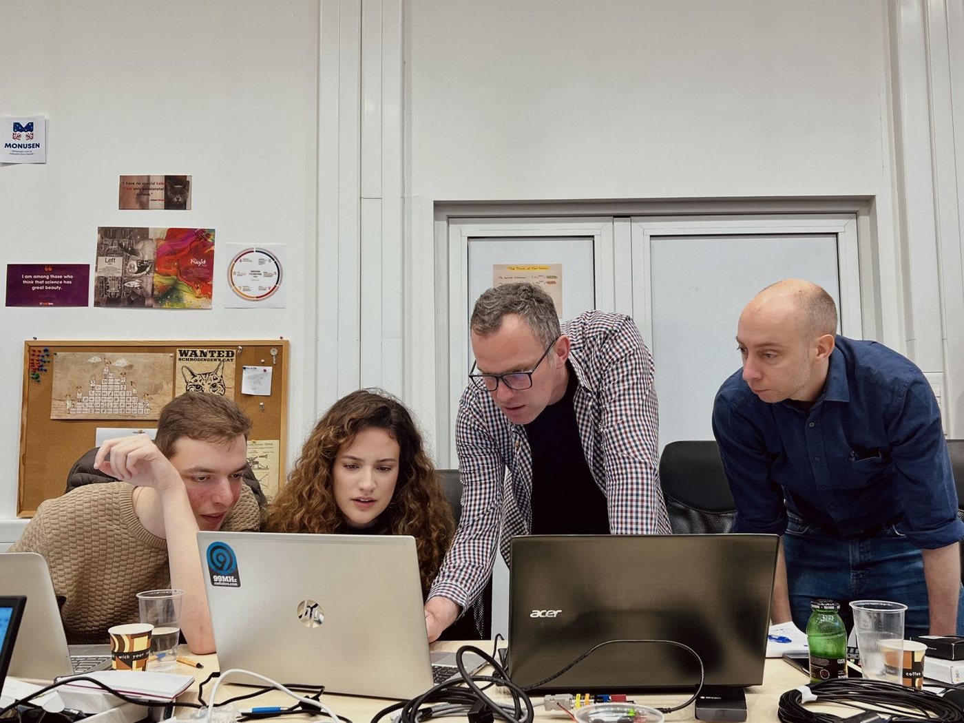 Researchers working through a problem together at a laptop in the lab