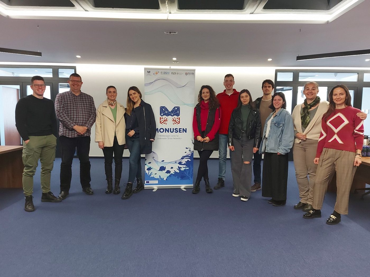MONUSEN team gathered beside the project banner